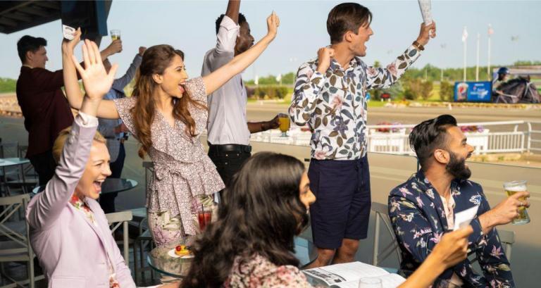 a group of people cheering for the jockeys in the race